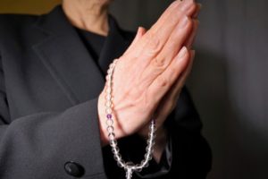 喪服で数珠をもって手を合わせる女性の画像